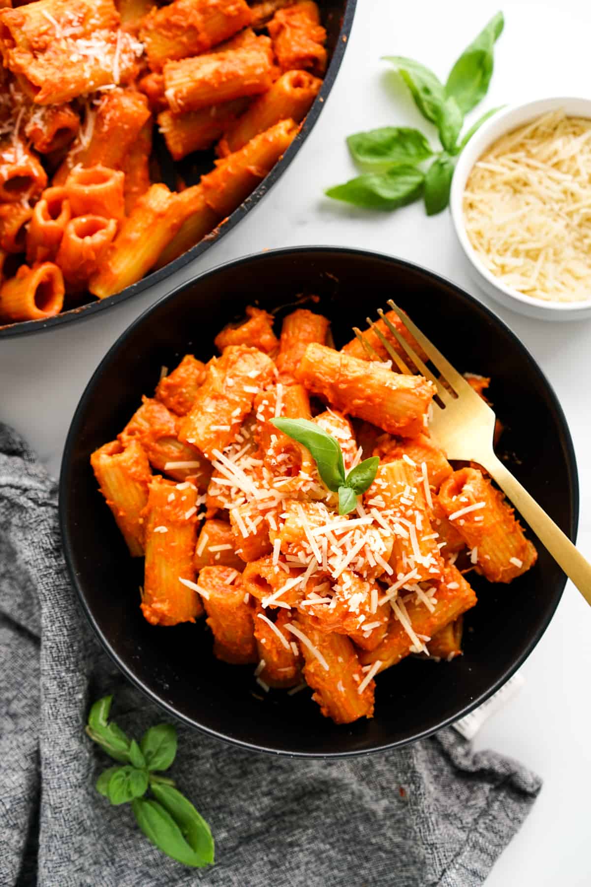 A bowl of rigatoni alla vodka topped with grated Parmesan and fresh basil