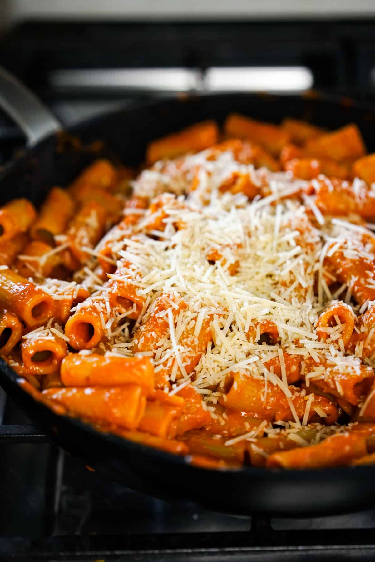 A skillet of rigatoni alla vodka topped with grated Parmesan